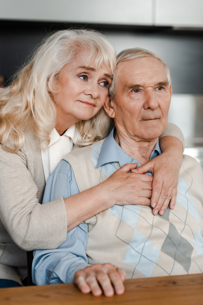 szomorú idősebb feleség és férj ölelkeznek és otthon ülnek a karanténban - Fotó, kép