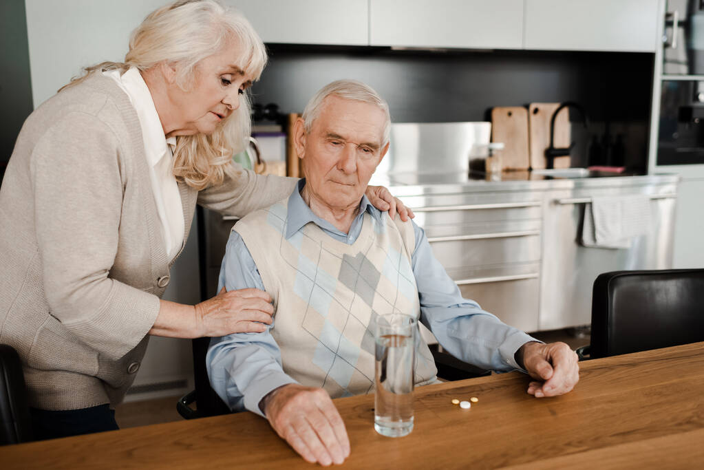 esposa anciana y marido enfermo con pastillas y vaso de agua en casa en cuarentena
 - Foto, Imagen