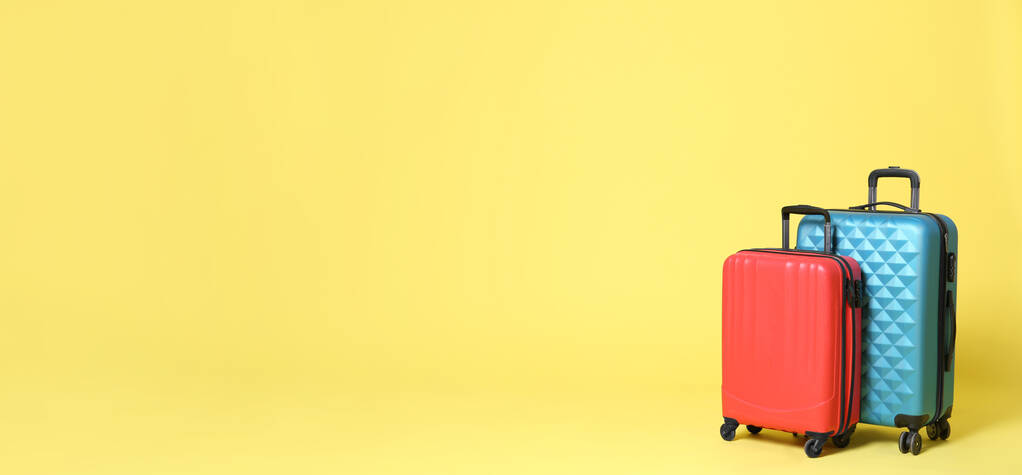 Elegantes maletas sobre fondo amarillo, espacio para texto. Diseño de banner
  - Foto, imagen