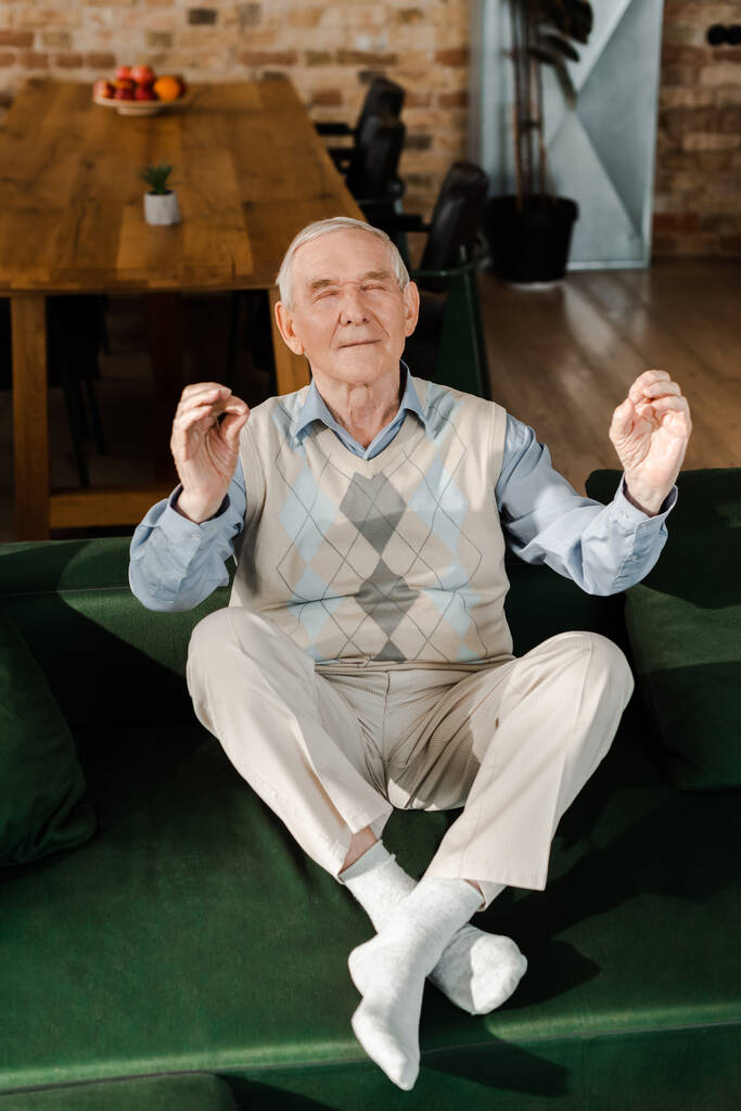 onnellinen iäkäs mies meditoi suljetuin silmin kotona itsensä eristämisen aikana - Valokuva, kuva
