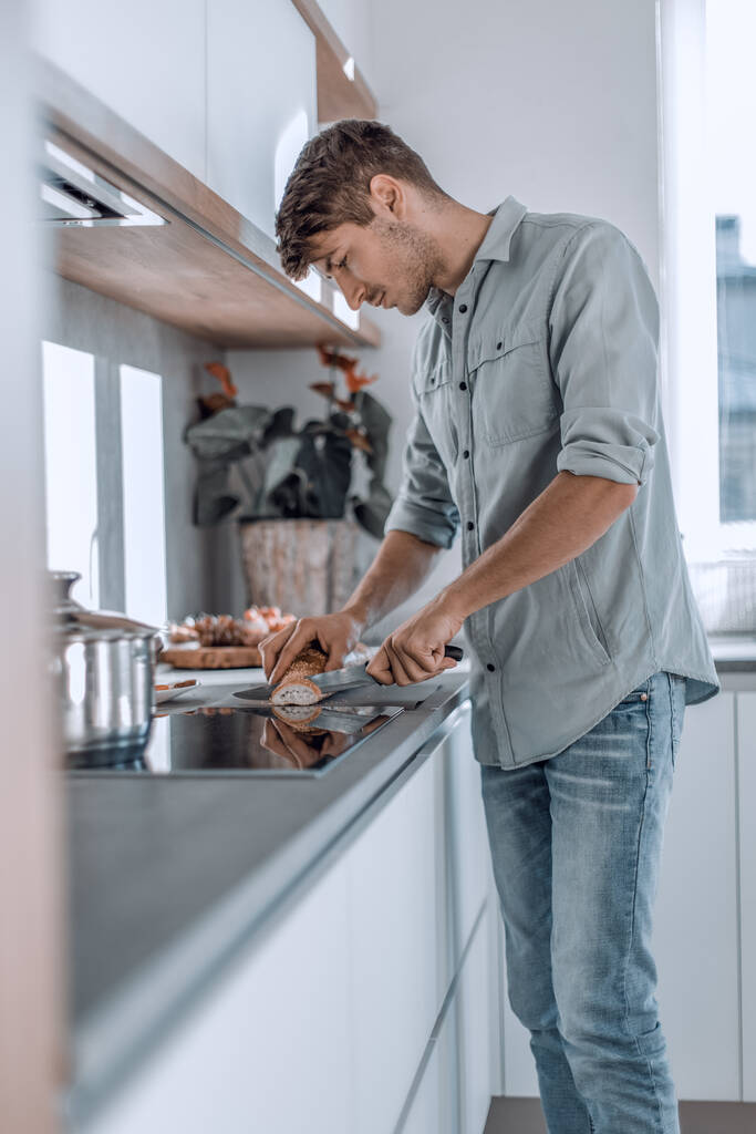 Junger Mann bereitet Frühstück in seiner Küche zu - Foto, Bild