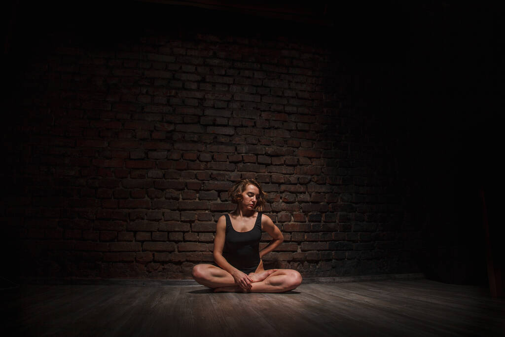 Girl in black swimsuit does yoga against the background of a brick wall - Photo, Image