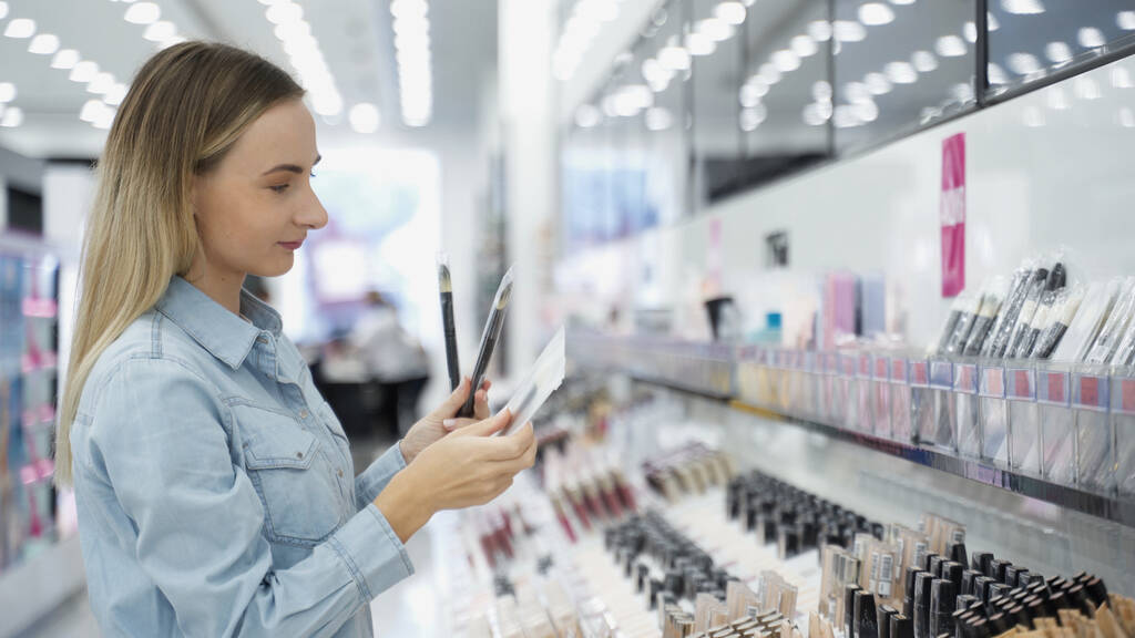 Mulher escolhe pincéis de maquiagem na loja
 - Foto, Imagem