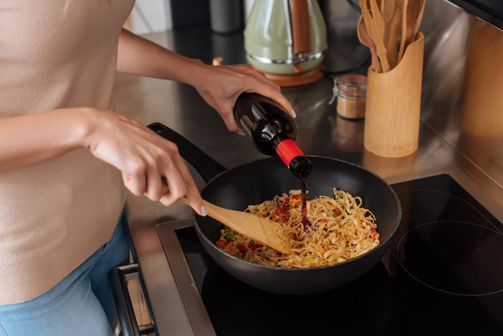 vista cortada da mulher derramando vinho tinto em wok enquanto prepara macarrão tailandês
 - Foto, Imagem
