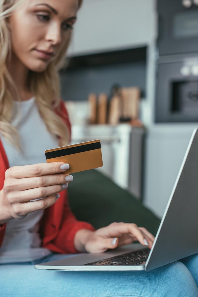 foco seletivo da mulher jovem usando laptop enquanto segurando cartão de crédito
 - Foto, Imagem