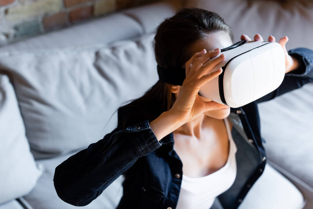 Selektiver Fokus einer jungen Frau, die Virtual-Reality-Headset berührt  - Foto, Bild