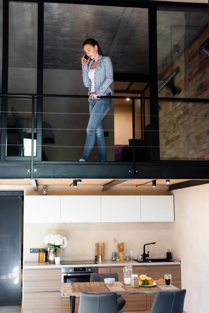 fiatal nő beszél okostelefonon, miközben áll a második emeleten duplex apartman  - Fotó, kép