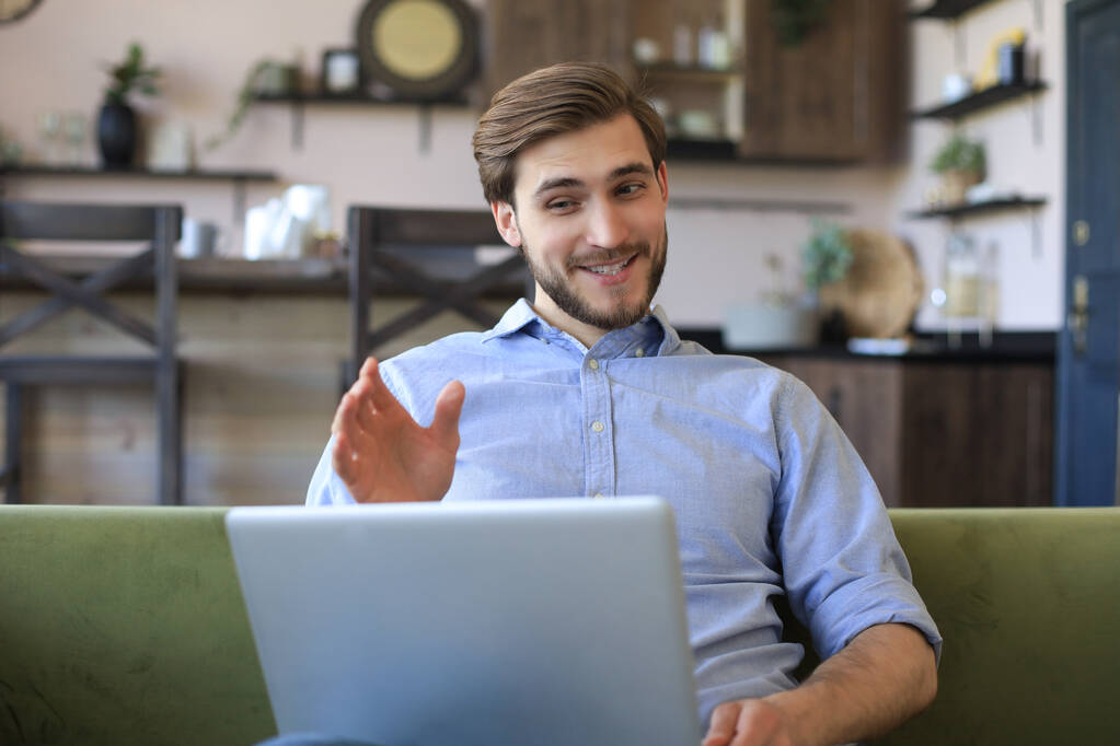 Smiling businessman greeting colleagues in video conference and negotiating distantly from home - Photo, Image