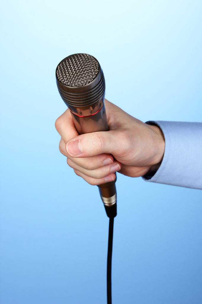 αρσενικό χέρι με μικρόφωνο σε μπλε φόντο - Φωτογραφία, εικόνα