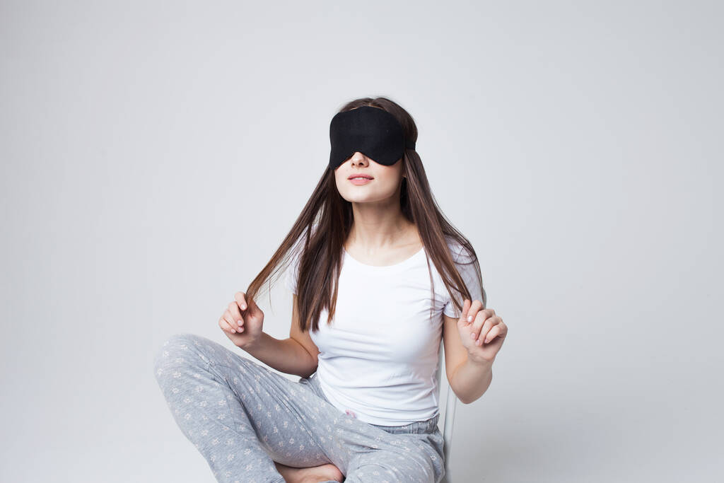 Slaap en slaperigheid, een jonge vrouw met een slaapmasker en in pyjama - Foto, afbeelding