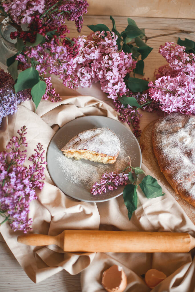 Tarta de manzana casera en una mesa de madera junto a un tazón de lilas. Tonificación suave. Enfoque selectivo
. - Foto, Imagen