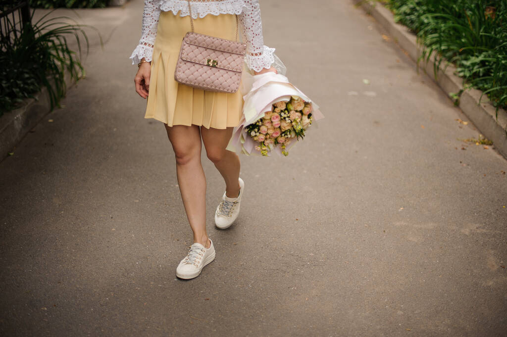 Девушка идет по улице с букетом в руках
. - Фото, изображение