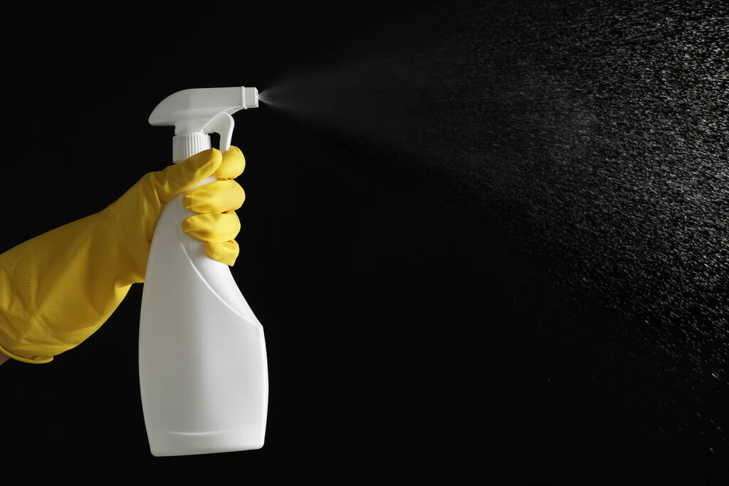 Person in gloves spraying detergent on black background, closeup. Space for text - Photo, Image