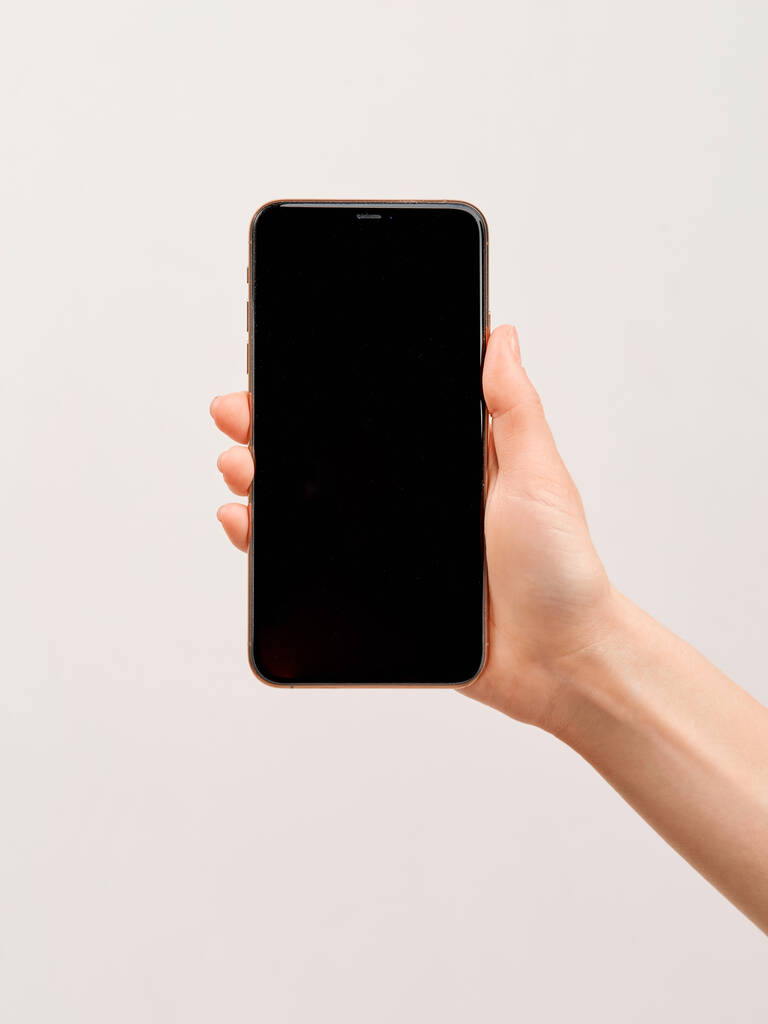 Moderni älypuhelin, jossa on suuri tyhjä näyttö valkoisella taustalla olevan tytön tyylikkäässä kädessä
. - Valokuva, kuva