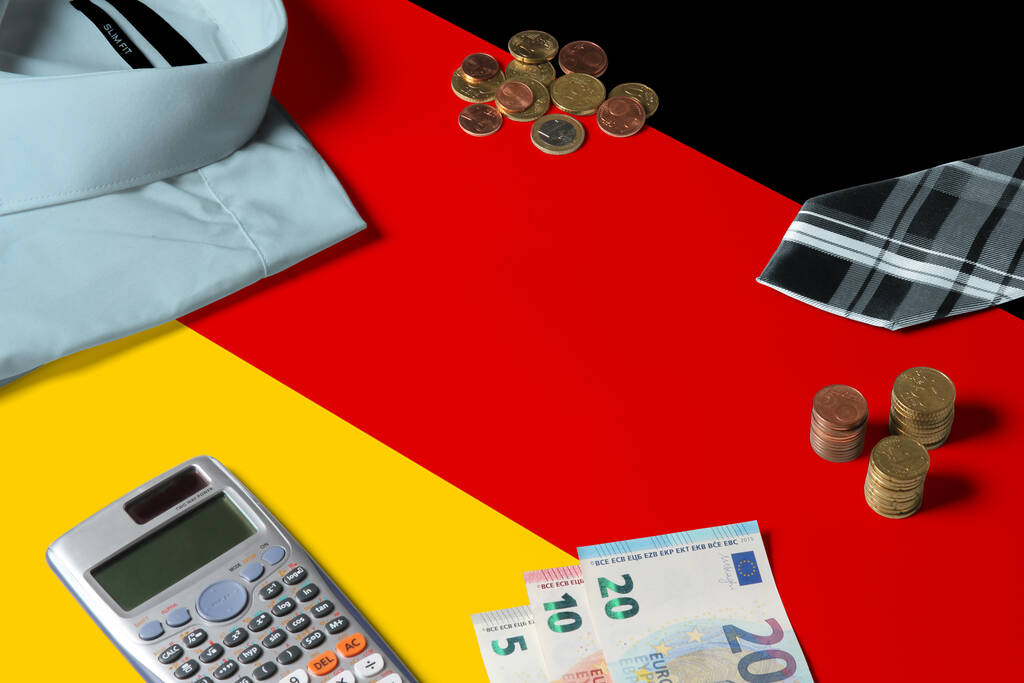 Flaga Niemiec na minimalnym stole koncepcyjnym pieniędzy. Monety i przedmioty finansowe na powierzchni flagi. Temat gospodarki narodowej. - Zdjęcie, obraz