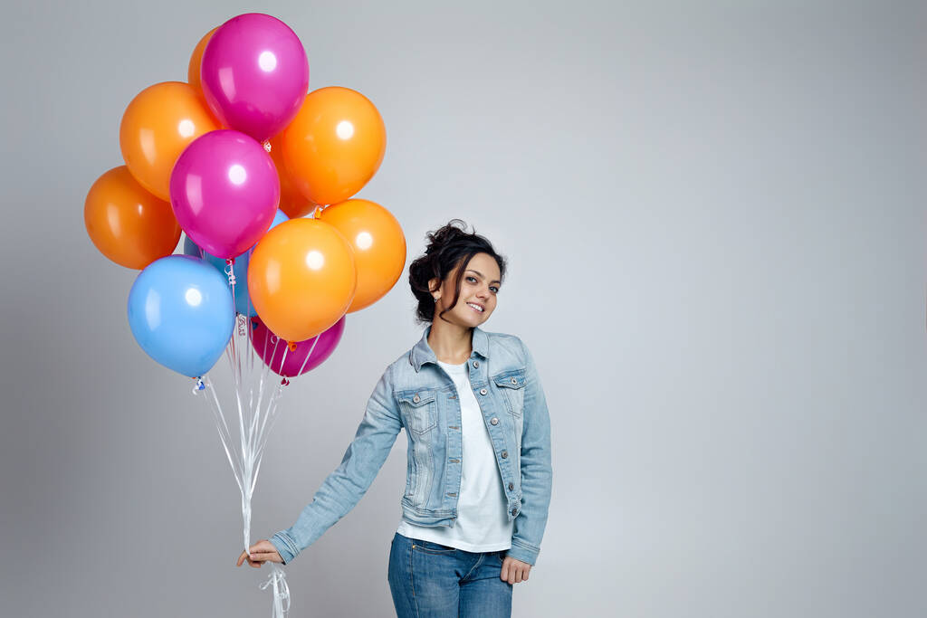 девушка в джинсе позирует с яркими красочными воздушными шарами
 - Фото, изображение