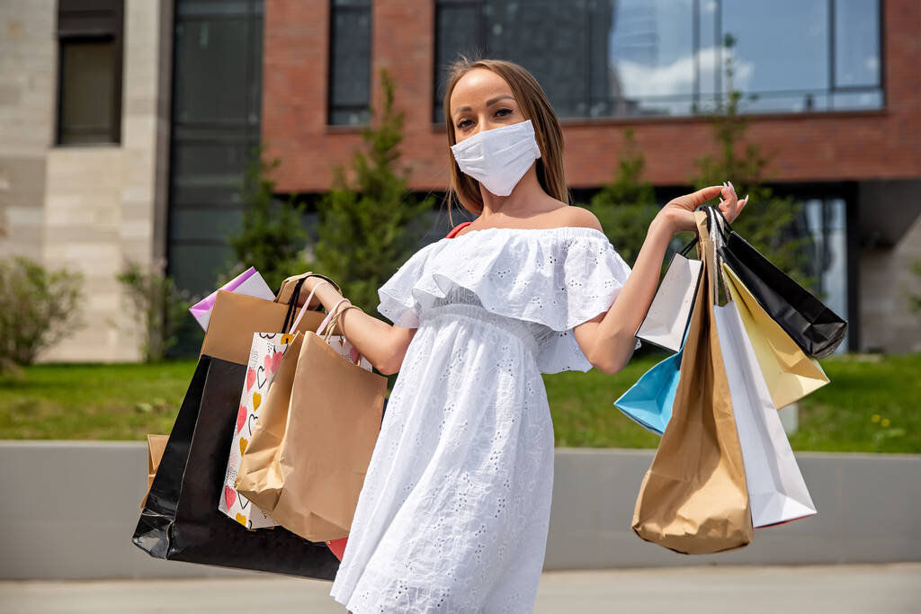 дівчина в медичній масці з покупками біля торгового центру
 - Фото, зображення