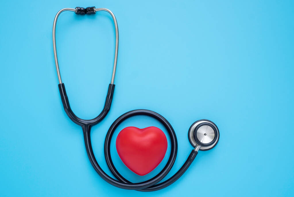 青い背景の検査のための医者の赤い心臓を持つ黒い聴診器。音を診断するための医療用聴診器。医療と心臓病の概念。コピースペースのある平らなレイアウト. - 写真・画像