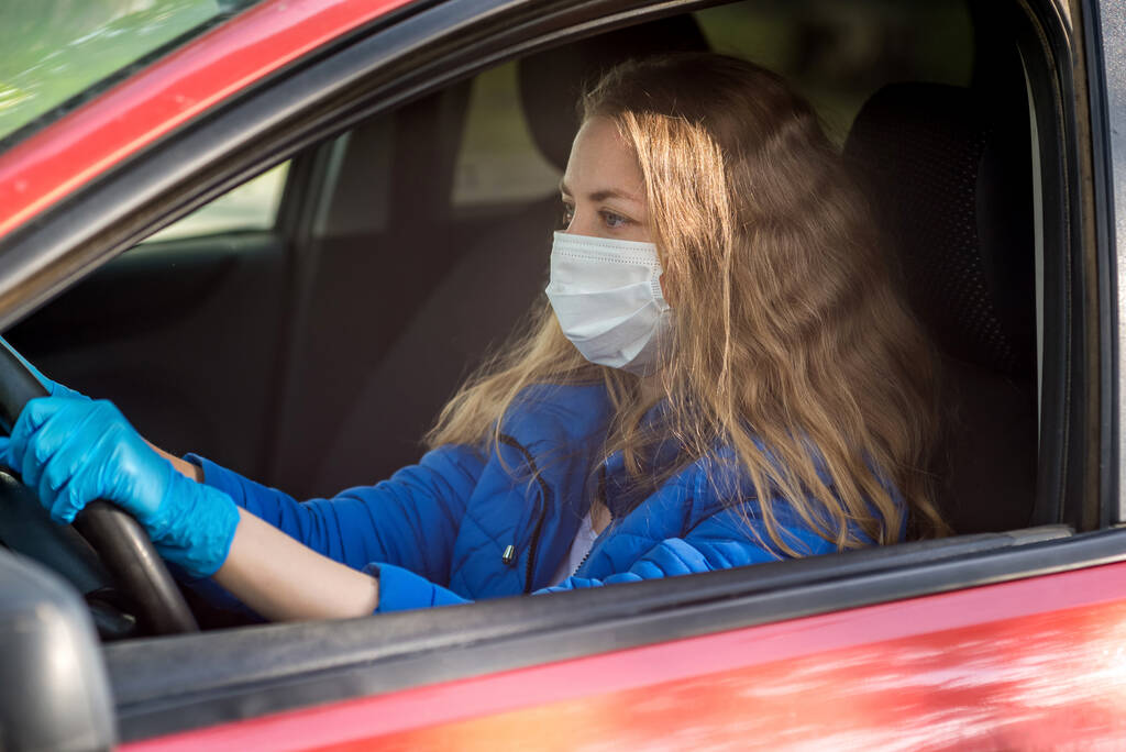 Nainen ajaa autoa suojaavassa naamiossa ja hanskat kädessä. Elämäntapa ja turvallinen ajo pandemian aikana koronavirus karanteenissa. Suojele kuljettajaa ja matkustajia. Uusi normaali ja moderni todellisuus
 - Valokuva, kuva