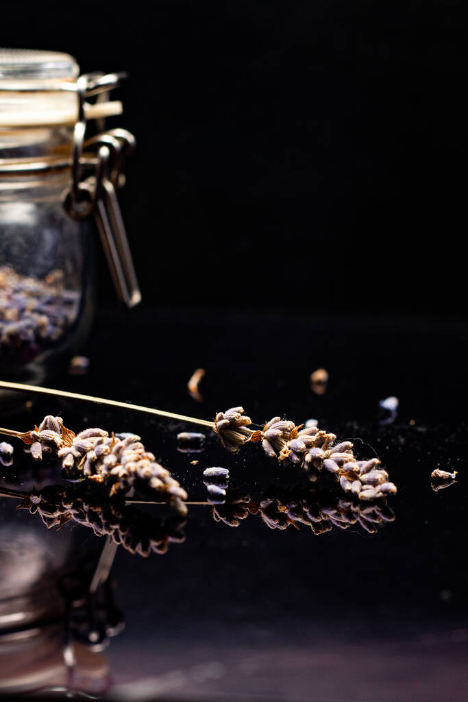 detailní pohled na levandulová semínka a skleněnou sklenici na černém pozadí - Fotografie, Obrázek