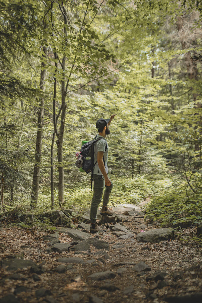 Young Man Traveler mit Rucksack entspannen im Freien mit felsigen Bergen im Hintergrund Sommerurlaub und Lifestyle-Wanderkonzept - Foto, Bild