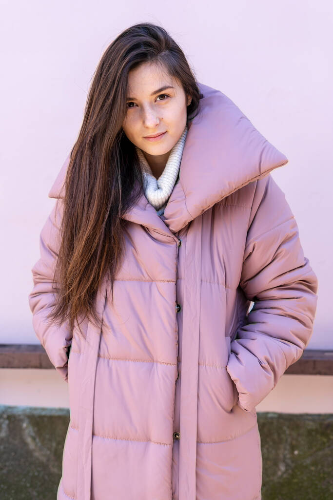 Mujer joven y elegante con abrigo cálido de color rosa o violeta, caminando por la calle de la ciudad en temporada fría. Moda de invierno, look elegante, atuendo en colores pastel. Modelo de tamaño más
. - Foto, imagen