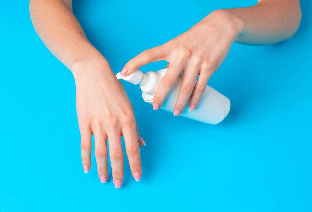 Femme main tenant bouteille de produit de soins de la peau sur bleu
 - Photo, image