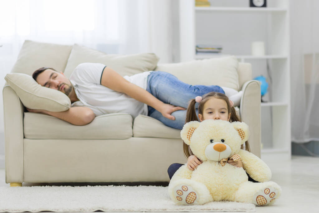 Dad is sleeping and his daughter sitting with white bear. - Photo, Image