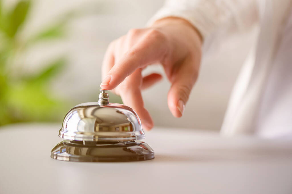 Hand of guest ringing in silver bell. reception desk with copy space. Hotel service. Selective focus - Photo, Image
