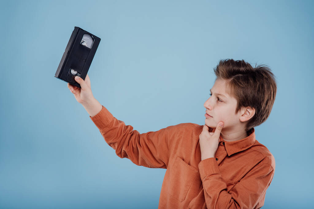 Verwirrter Junge erkundet Retro-Videokassette - Foto, Bild