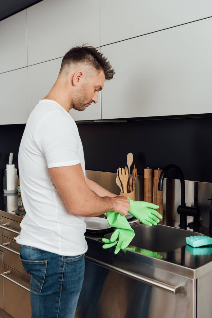 pohledný muž v gumové rukavici v kuchyni  - Fotografie, Obrázek