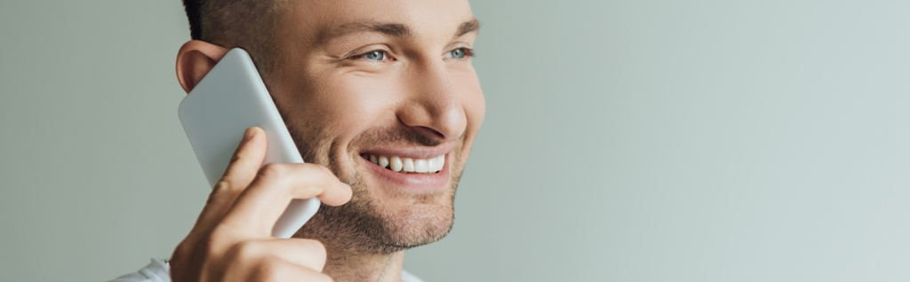 Horizontal crop of smiling man talking on smartphone isolated on grey  - Photo, Image