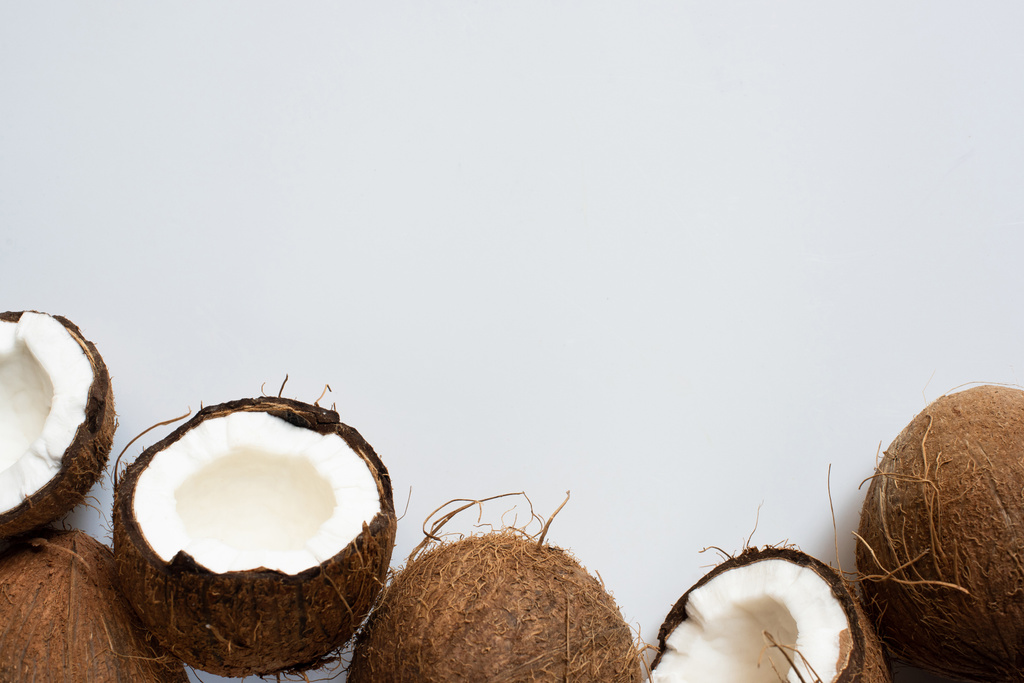 вид сверху на свежие вкусные целые кокосы и половинки на белом фоне
 - Фото, изображение