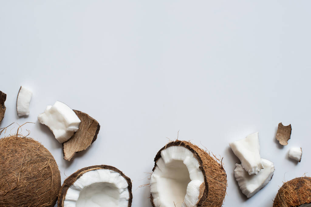 вид сверху на свежий вкусный цельный и потрескавшиеся кокосы на белом фоне
 - Фото, изображение
