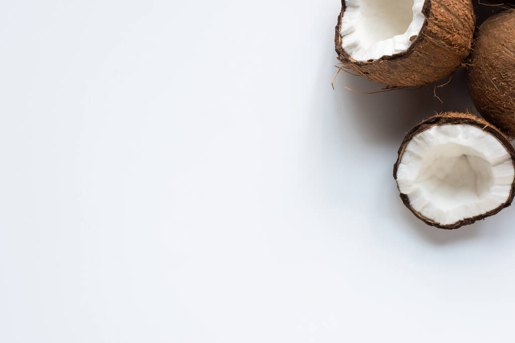 bovenaanzicht van verse smakelijke kokoshelften op witte achtergrond - Foto, afbeelding