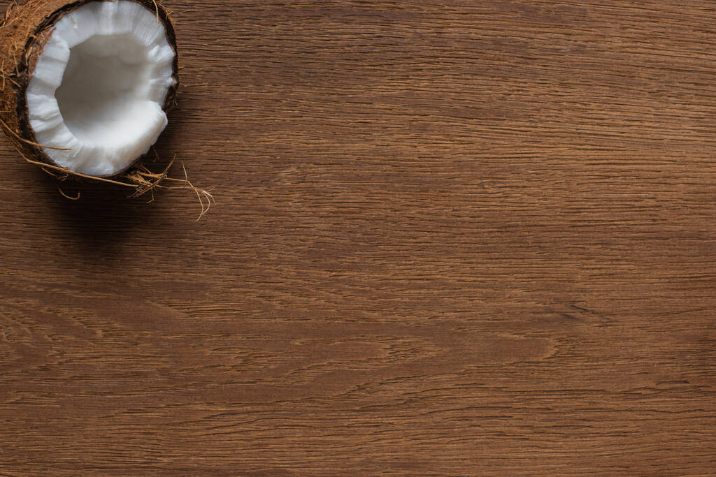 bovenaanzicht van verse smakelijke kokosnoot helft op houten tafel - Foto, afbeelding