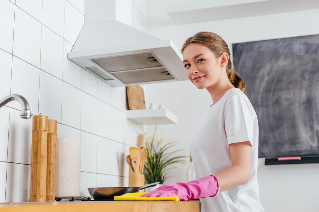 ピンクのゴム手袋のクリーニングキッチンで陽気な女性の選択的な焦点  - 写真・画像