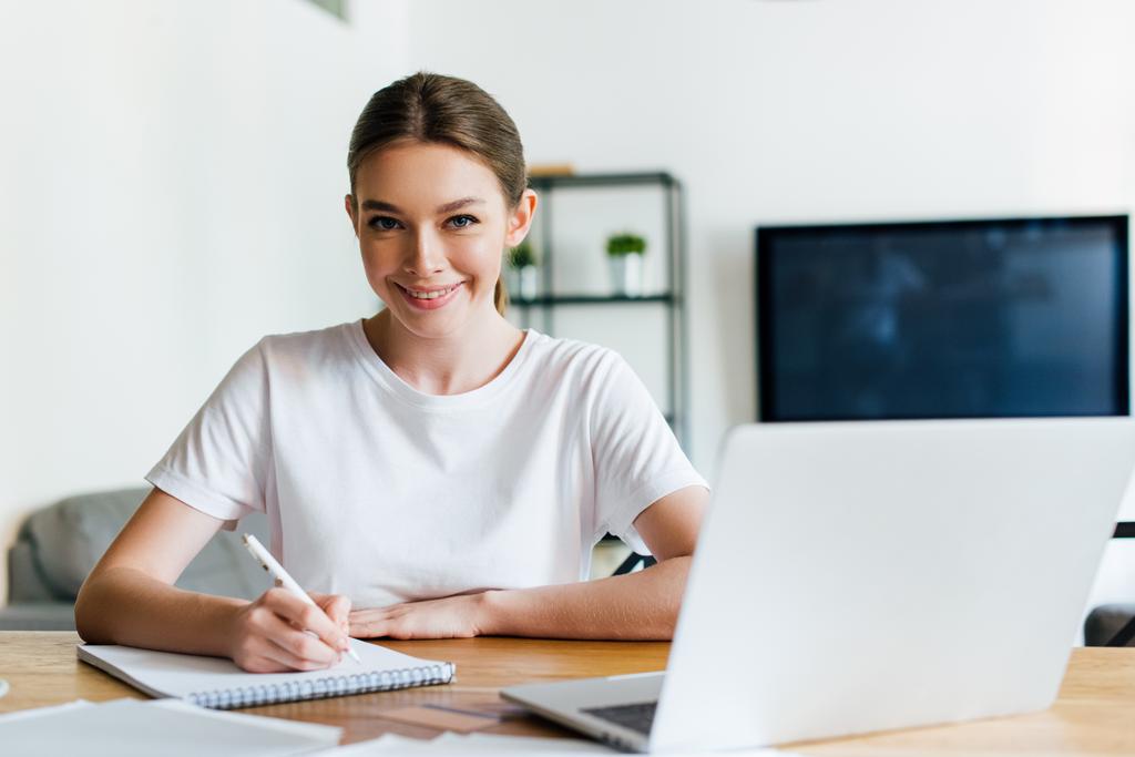 вибірковий фокус щасливої жінки, що тримає ручку біля ноутбука та ноутбука
 - Фото, зображення