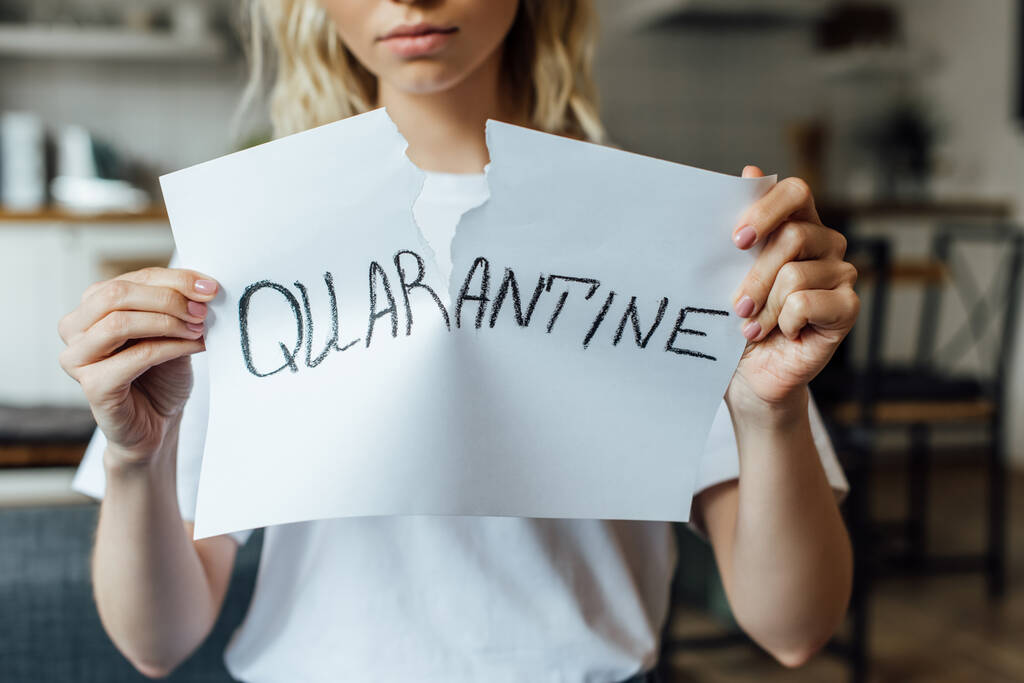Cropped view of young woman tearing card with quarantine lettering at home  - Photo, Image