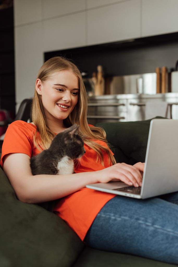 foyer sélectif de pigiste heureux en utilisant un ordinateur portable près du chat dans le salon
  - Photo, image