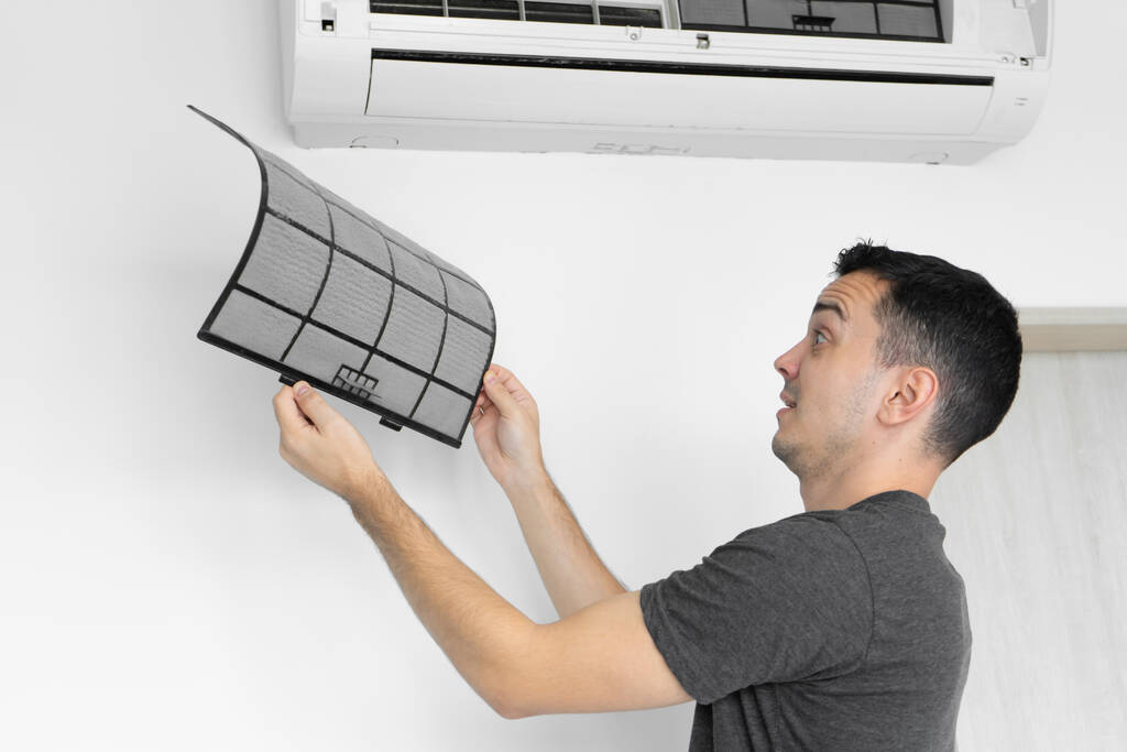 De man reinigt het filter van de airconditioner van stof. Zeer vuile airconditioner filter. Zorg voor klimaatapparatuur - Foto, afbeelding