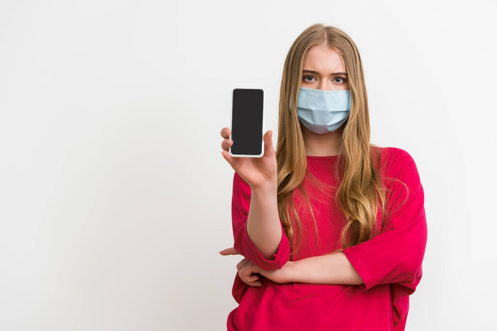 mulher em máscara médica segurando smartphone com tela em branco isolado no branco
  - Foto, Imagem