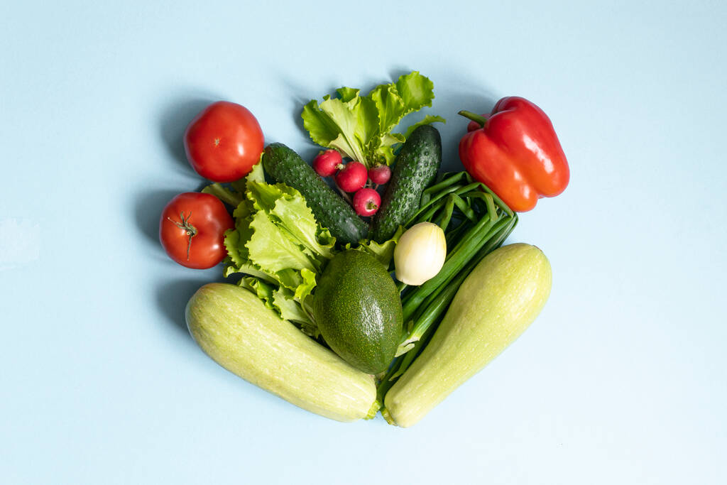 Assortment of fresh green red organic vegetables. zucchini, cucumber, onion, avocado, lettuce, pepper, tomatoes and radish on a blue background. flat lay - Photo, Image