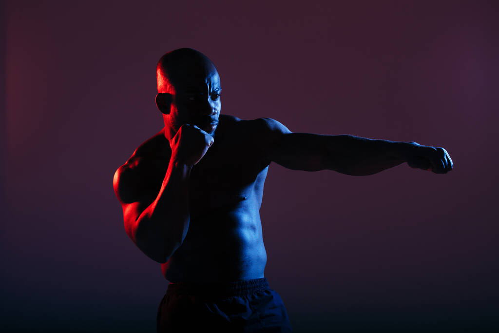 Boxer nero professionale boxe e fare esercizi prima di una gara di lotta leggera al neon
 - Foto, immagini