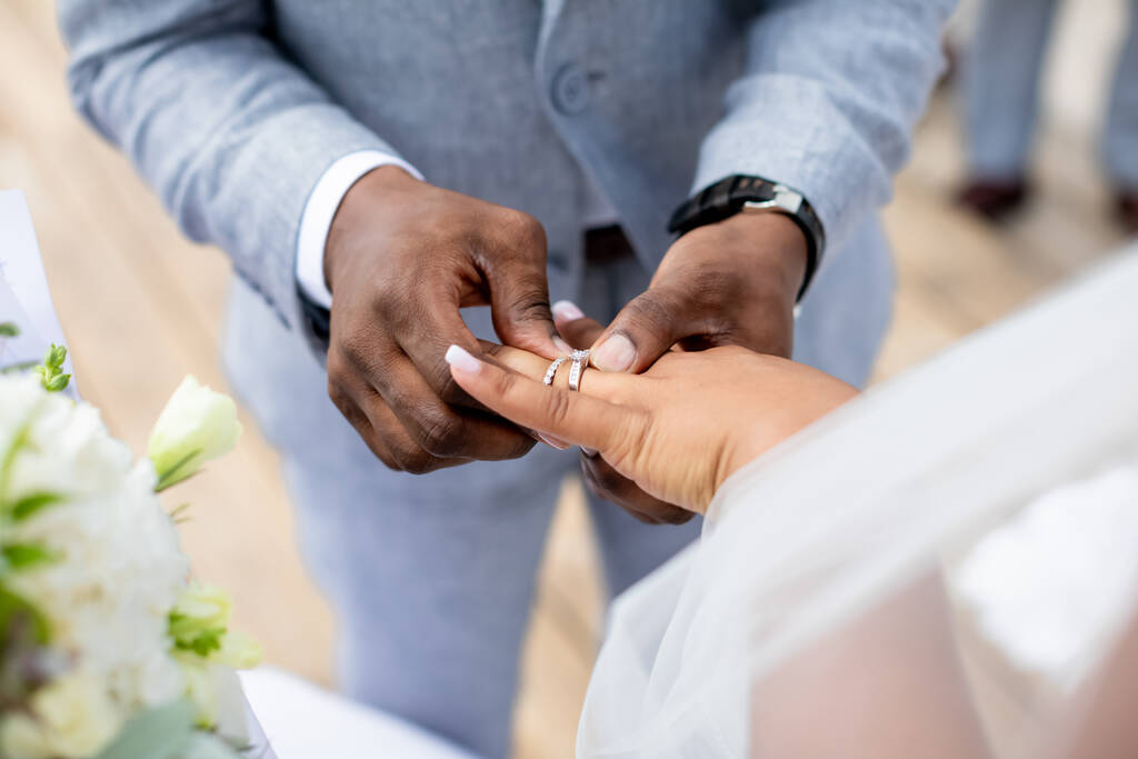 Bruid en bruidegom ruilen trouwringen close-up tijdens symbolische nautische decor bestemming bruiloft huwelijk op zandstrand voor de oceaan in Punta Cana, Dominicaanse Republiek   - Foto, afbeelding