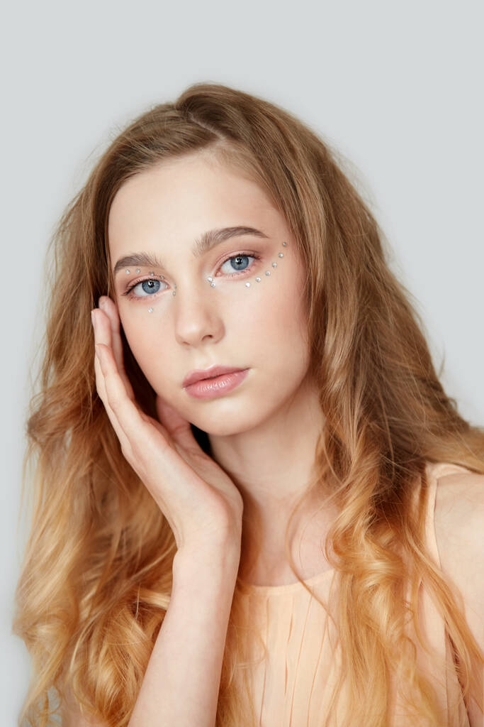 Το βλέμμα ενός νεαρού όμορφου κοριτσιού με ξανθά μαλλιά και μπλε μάτια. - Φωτογραφία, εικόνα