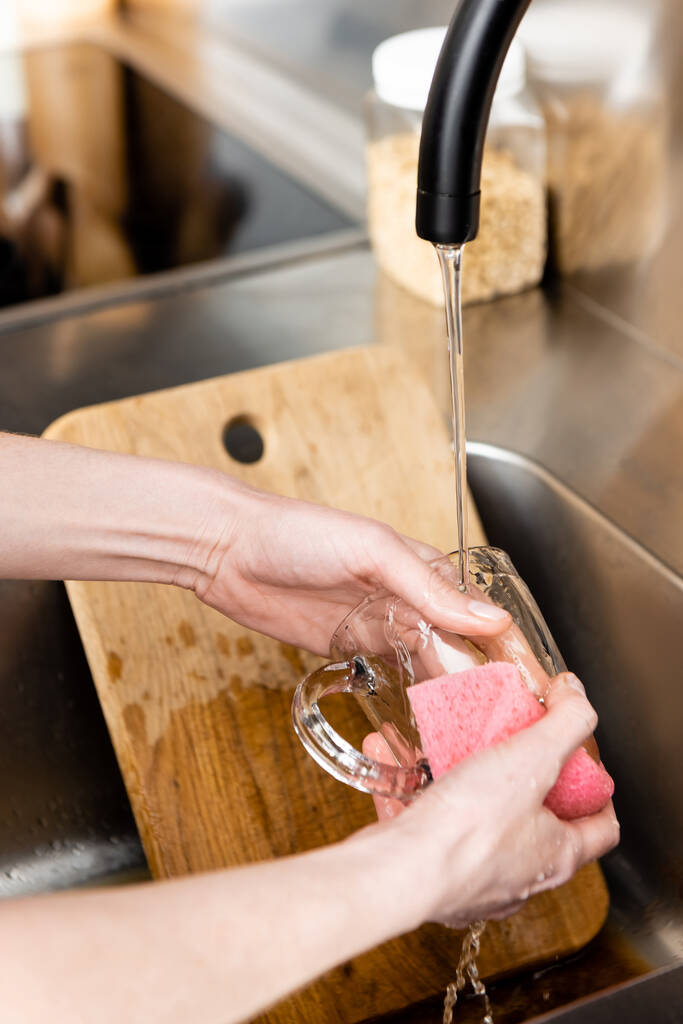 Vista recortada de la mujer taza de limpieza cerca de la tabla de cortar en el fregadero de cocina
  - Foto, Imagen