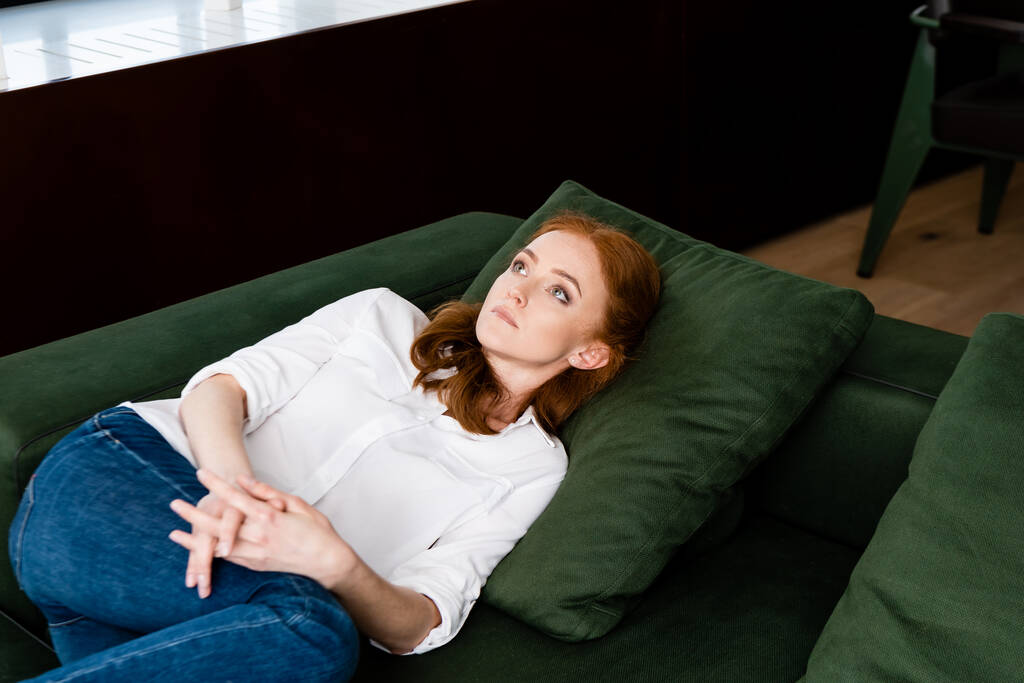 Selektywne skupienie na depresji kobiety z zaciśniętymi dłońmi leżącej na kanapie  - Zdjęcie, obraz