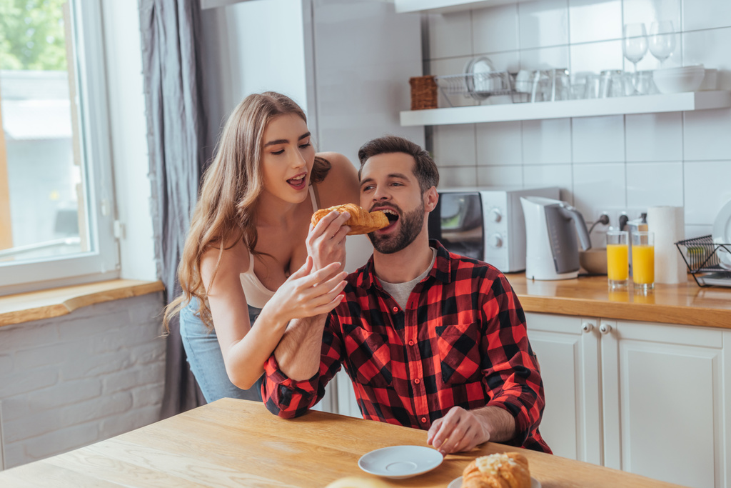 красивая молодая женщина кормит парня вкусным круассаном вкусный круассан
 - Фото, изображение