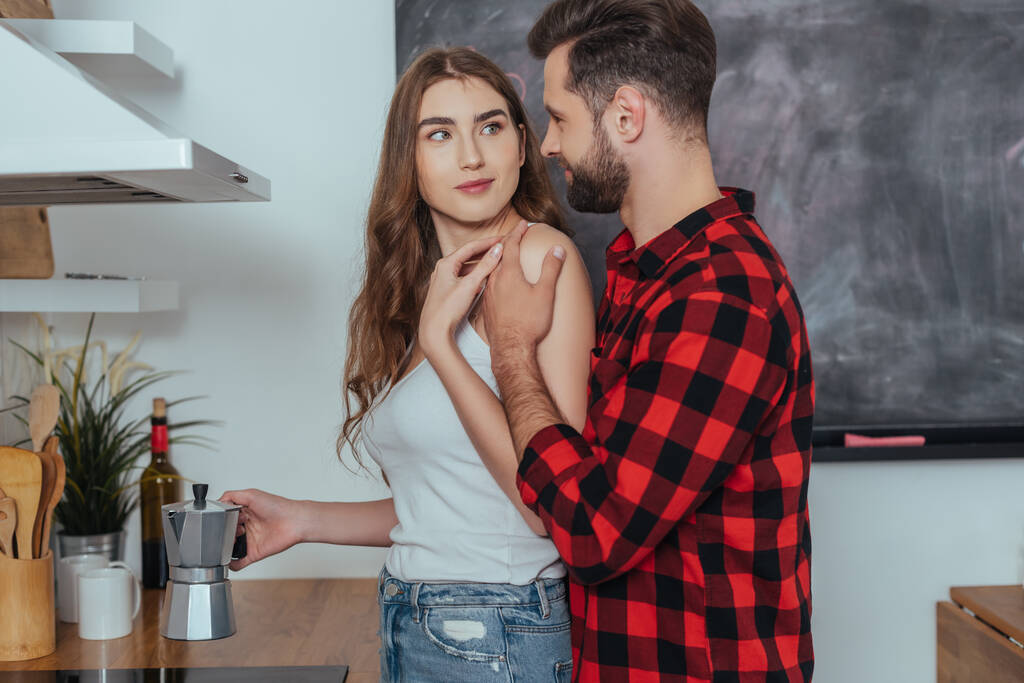 jovem homem tocando ombro de sorrindo namorada fazendo café em geyser cafeteira
 - Foto, Imagem